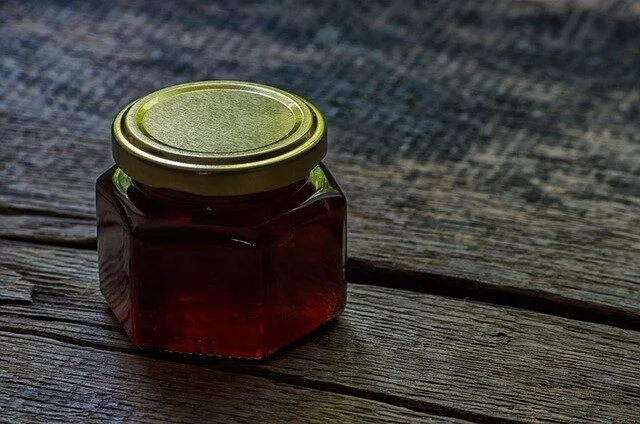 Słoik miodu na drewnianym podkładzie — naturalny produkt z pasieki jako element zestawu prezentowego
